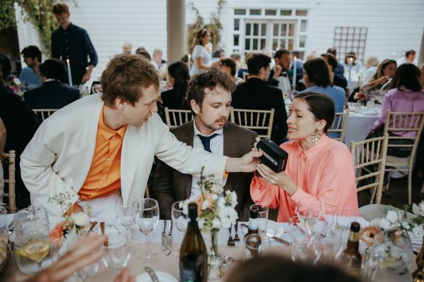 Man with orange silk shirt hands bag to female guest