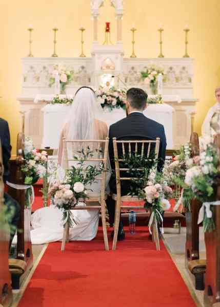 Bride and groom from behind veil detail red aisle carpet in shot