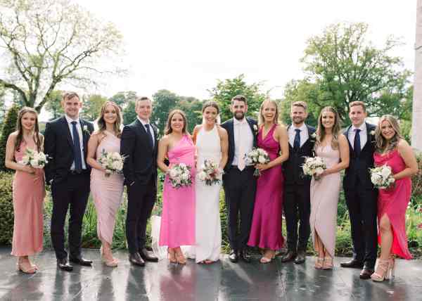 Bride groom bridesmaids and groomsmen cheers with bouquet