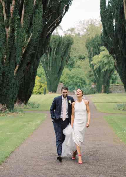 Bride and groom walk along the pathway to garden forest