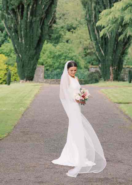 Bride on her own stands on pathway in garden