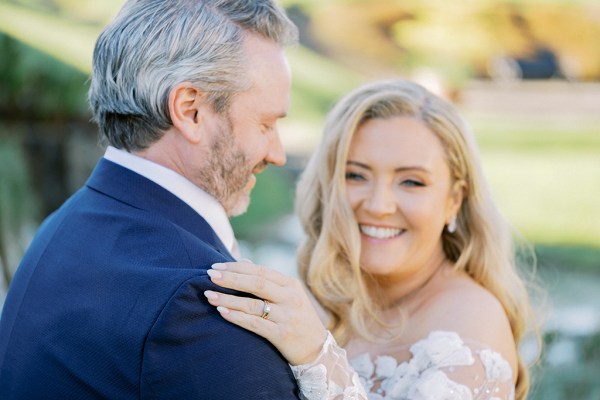 Bride faces camera and smiles with groom