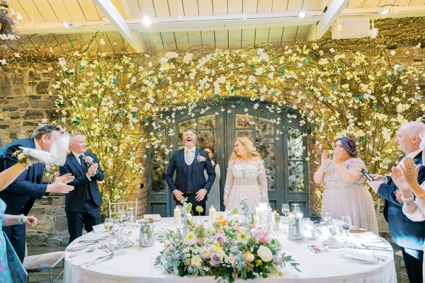 Bride groom and family members at table they clap fairy lights in background