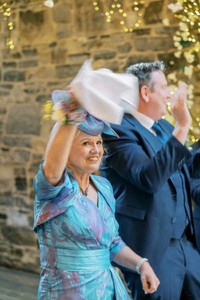 Woman wearing blue hat and dress waves to the couple