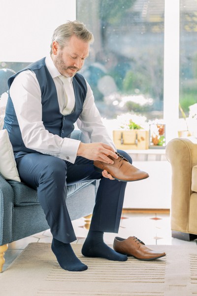 Groom puts on his brown wedding brogue shoes