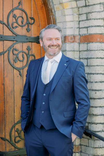 Groom poses in front of church exterior door