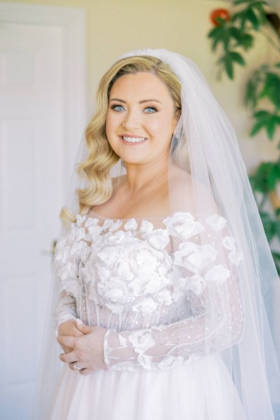 Bride poses for the camera veil and lace dress detail