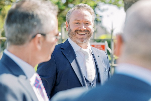 Groom smiles at his groomsmen