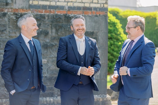 Groom and his groomsmen smile laugh