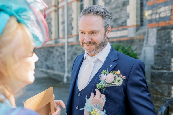 Groom smiles at mother outside of church