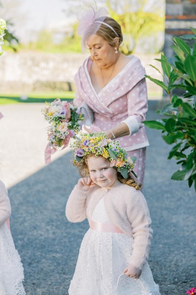 Red headed little girl with flower floral head band smiles for the camera with grandmother