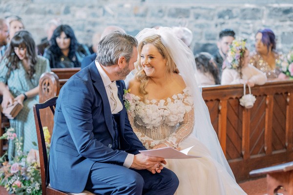 Bride and groom smile at each other as they are seated