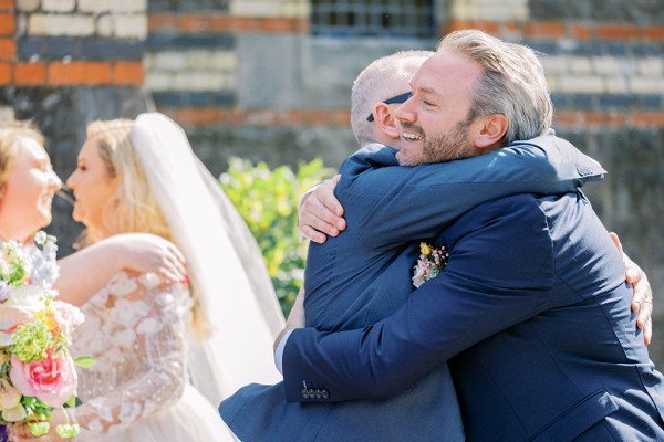 Groom hugs male friend