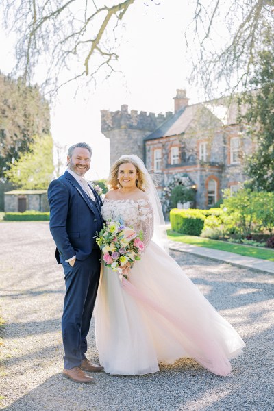 Bride and groom pose in front of wedding venue