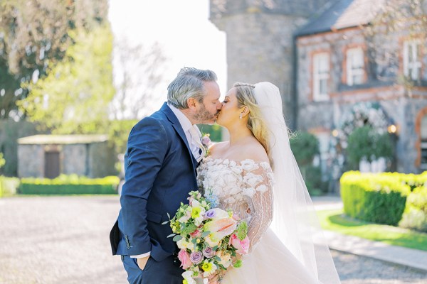 Bride and groom kiss in front of wedding venue