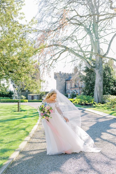 Bride poses on pathway with flowers bouquet