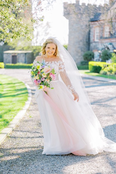 Bride poses on pathway with flowers bouquet