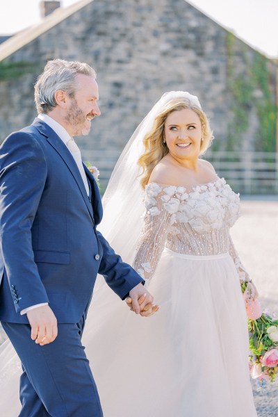 Bride and groom walk smiling holding hands