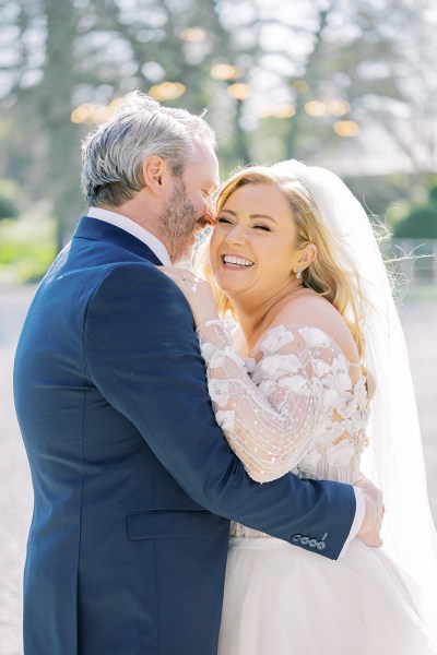 Bride and groom face each other smiling happy in forest laughing