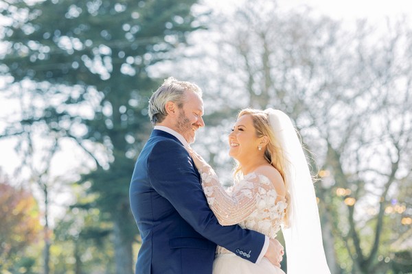 Bride and groom face each other smiling happy in forest