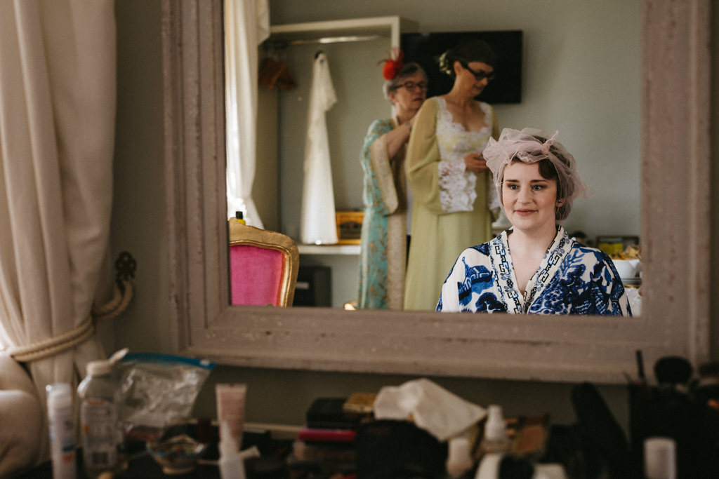 Bride smiles as she looks at herself in the mirror reflection