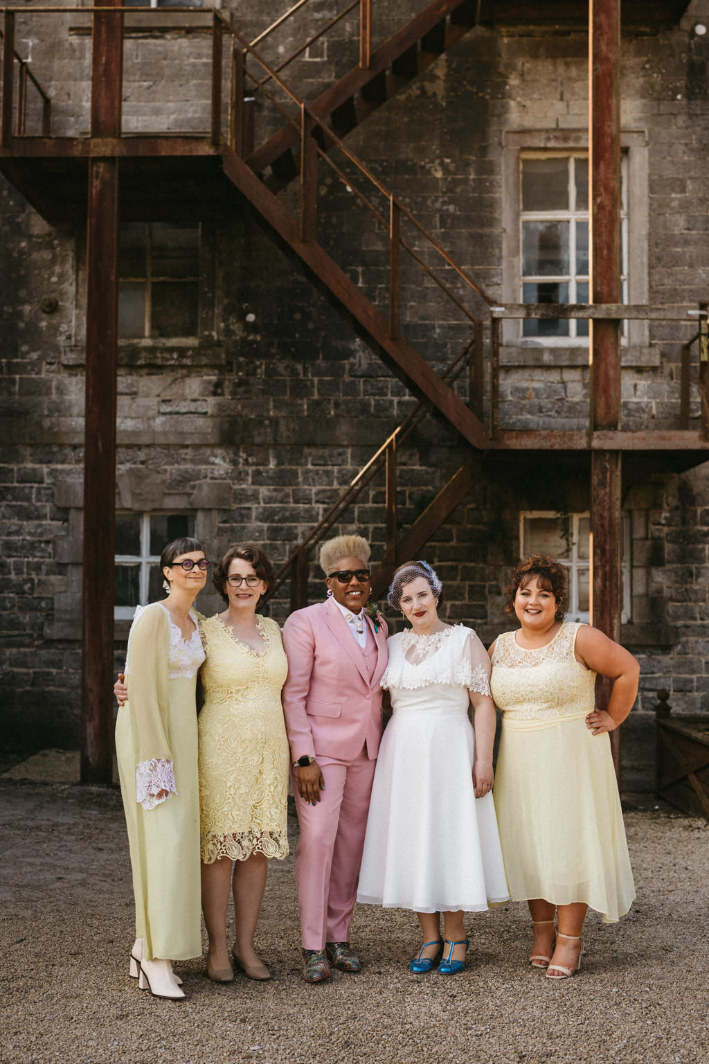 Bride in middle pink suit groomsmen and bride in white dress and bridesmaids