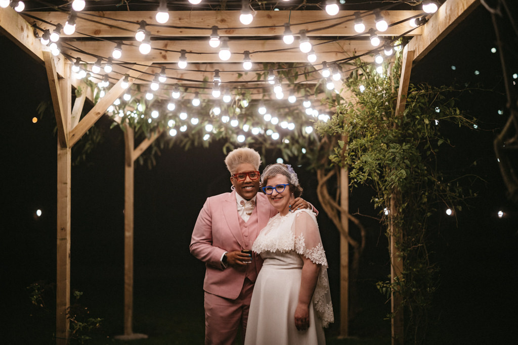 Brides pose under fairy lights