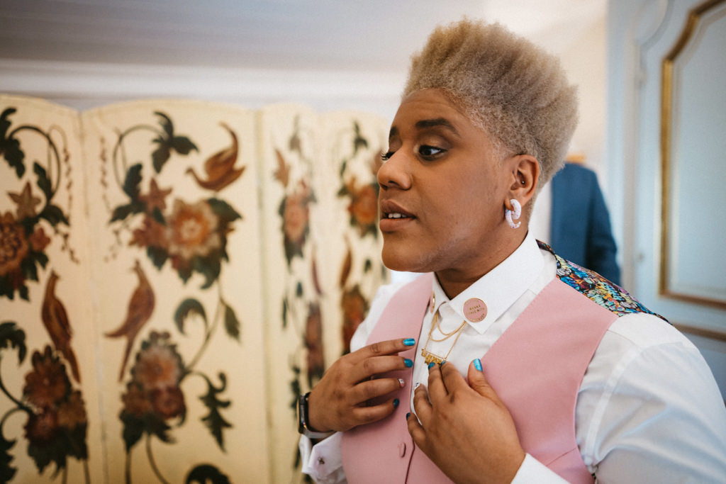 Bride places on gold necklace under her collar