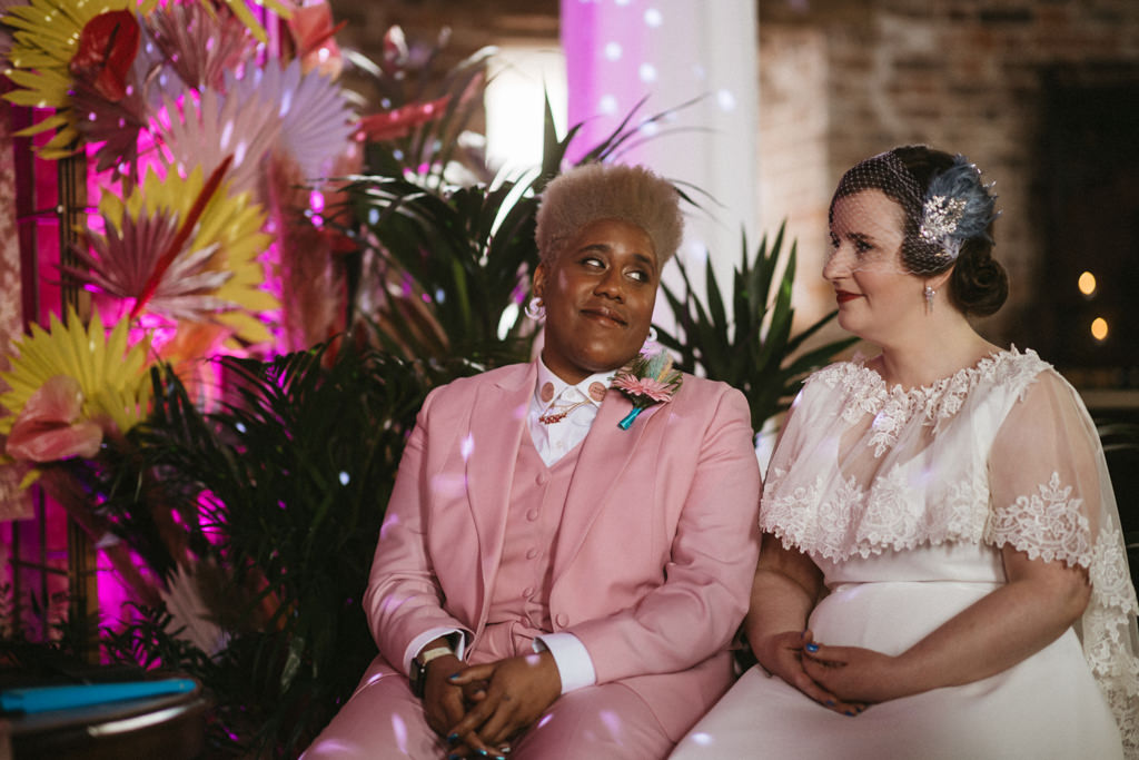 Bride looks at her bride as they sit during ceremony