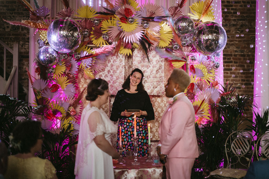 Celebrant smiling at two brides at alter