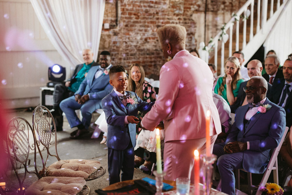 Two brides disco ball creating reflection guests seated alter candles lit with little boy son