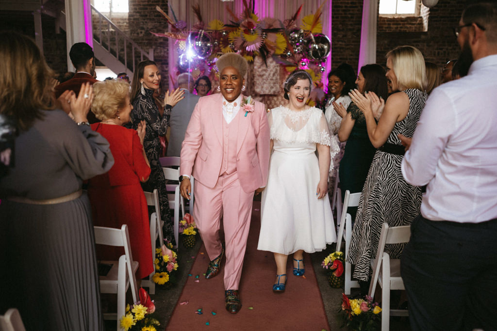 Guests clap for the couple just wed two brides exit church