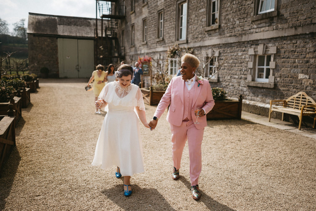 Brides hand in hand walking outside venue