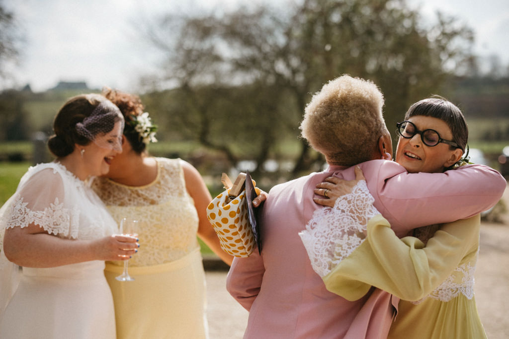 Bride hugs friend bride chatting to bridesmaid