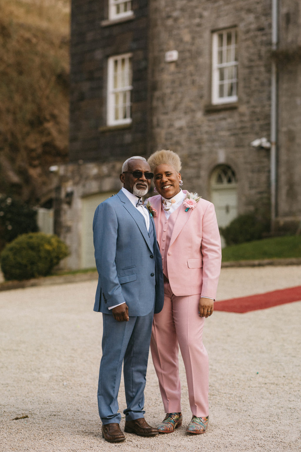 Bride and Father stand in front of red carpet venue in background