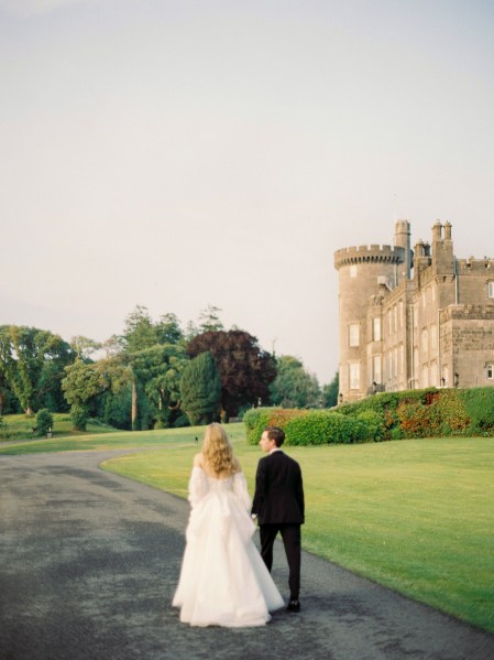 Bride and groom walk along the pathway to wedding venue