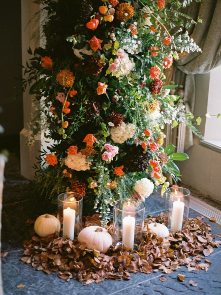 Candles lit in holders colourful autumnal flowers