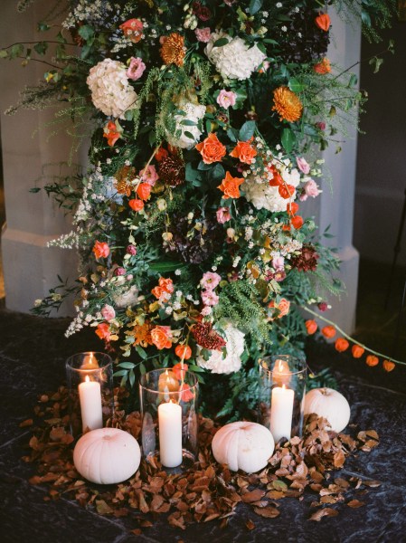 Candles lit in holders colourful autumnal flowers