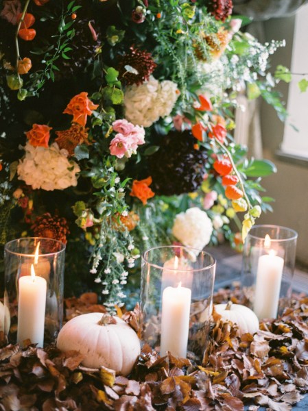 Candles lit in holders colourful autumnal flowers