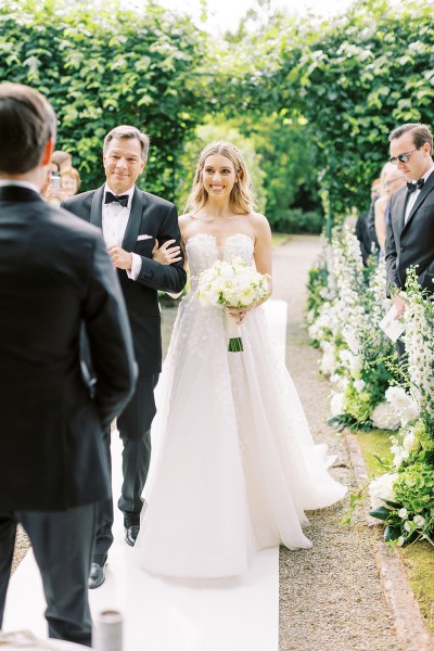 Father of the bride walks his daughter down the aisle approaching groom