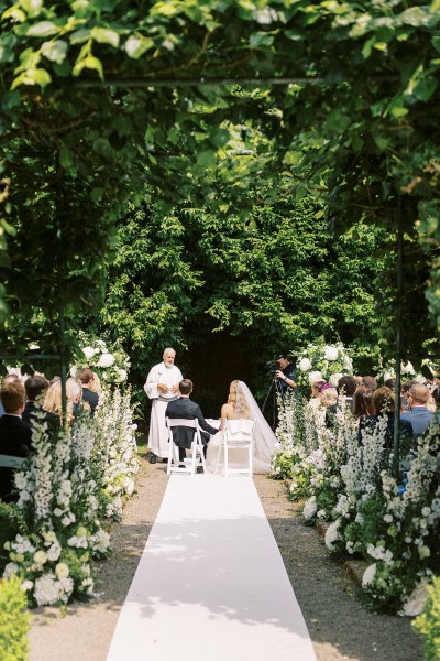 Wide shot view of bride and groom at the alter with priest and guests sitting