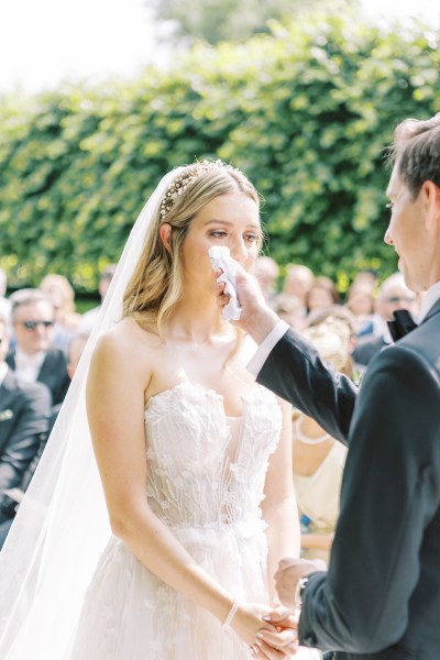 Emotional bride starts to cry at alter with groom they hold hands groom offers tissue