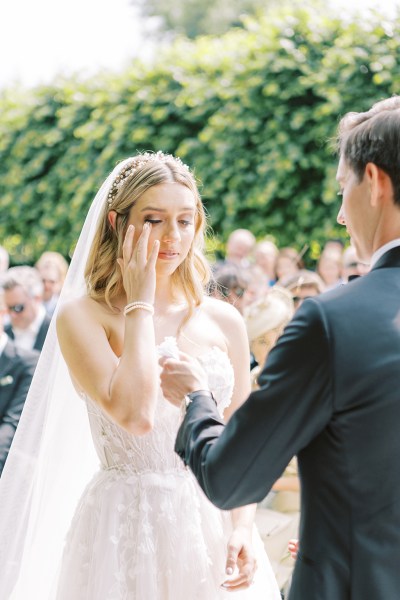 Emotional bride starts to cry at alter with groom they hold hands groom offers tissue