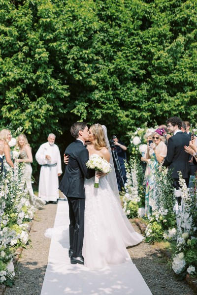 Bride and groom kissing at alter in front of guests