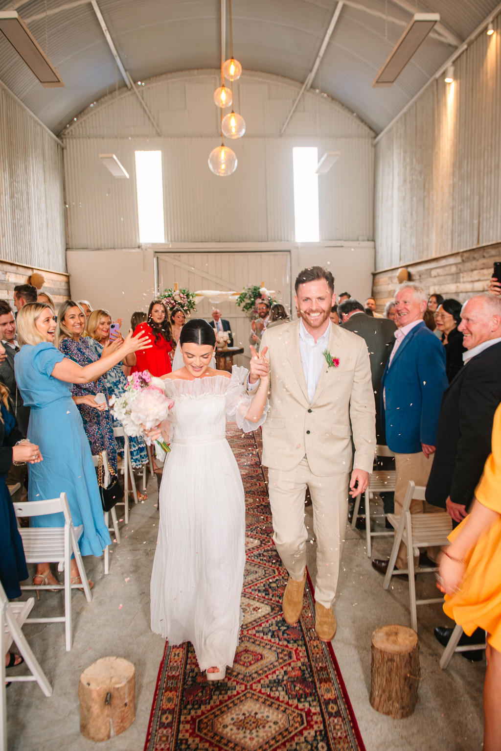 Bride and groom exit ceremony surrounded by guests