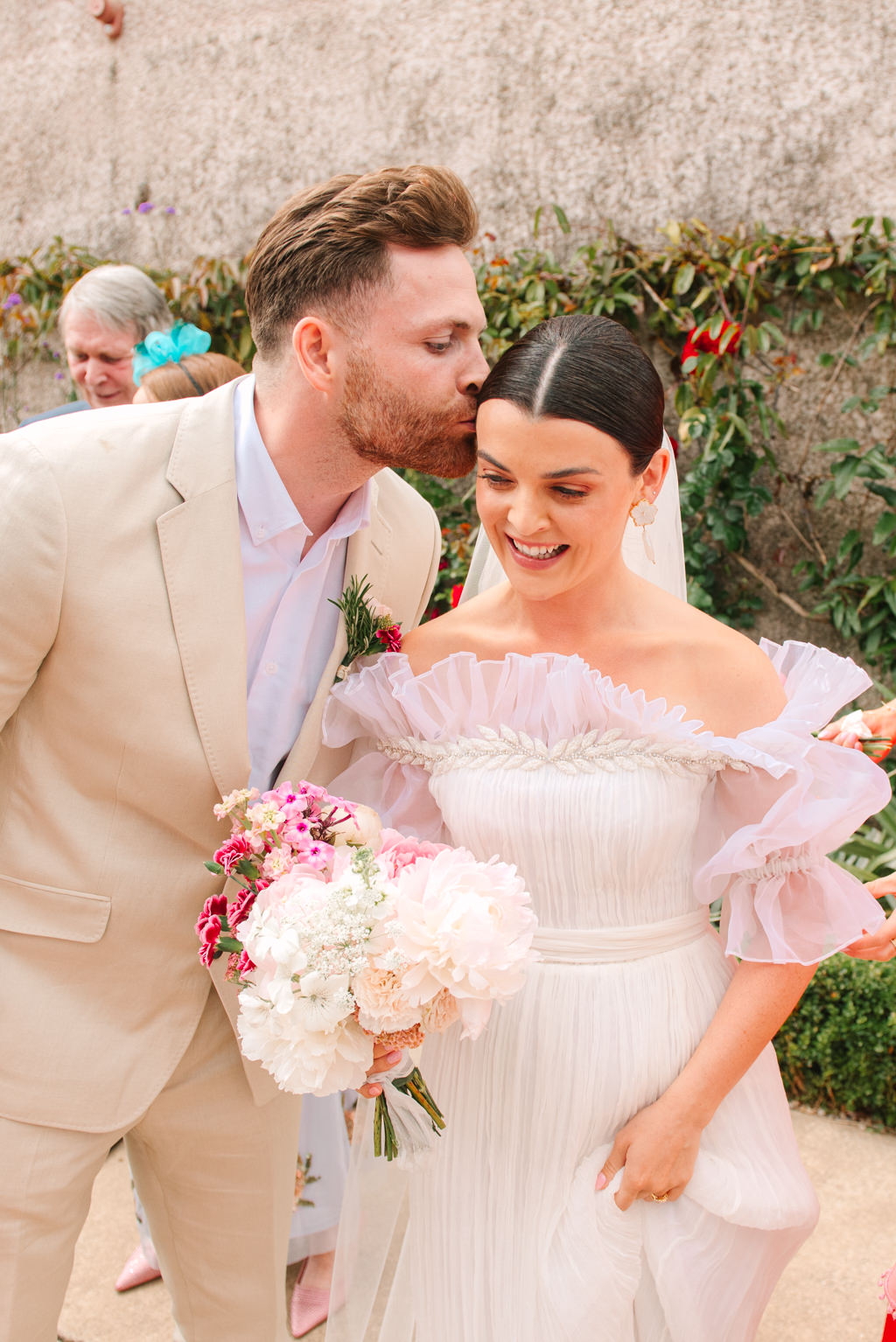 Groom kisses bride on the head as she smiles