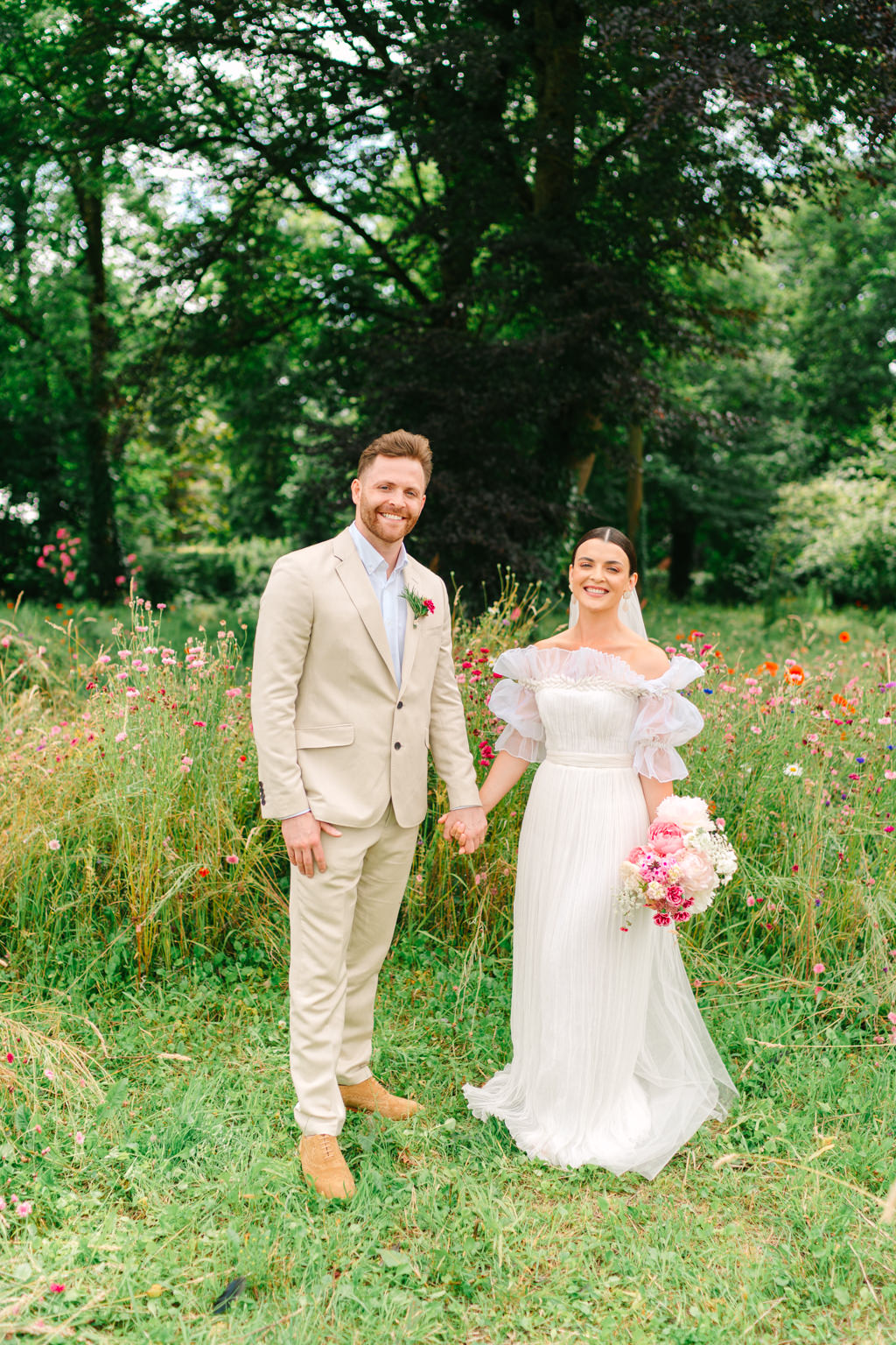 Bride and groom stand in the garden park holding hands