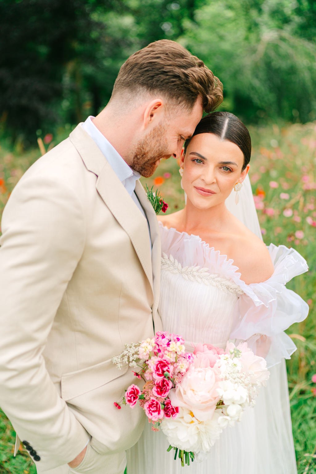 Bride and groom pose in garden park she holds bouquet