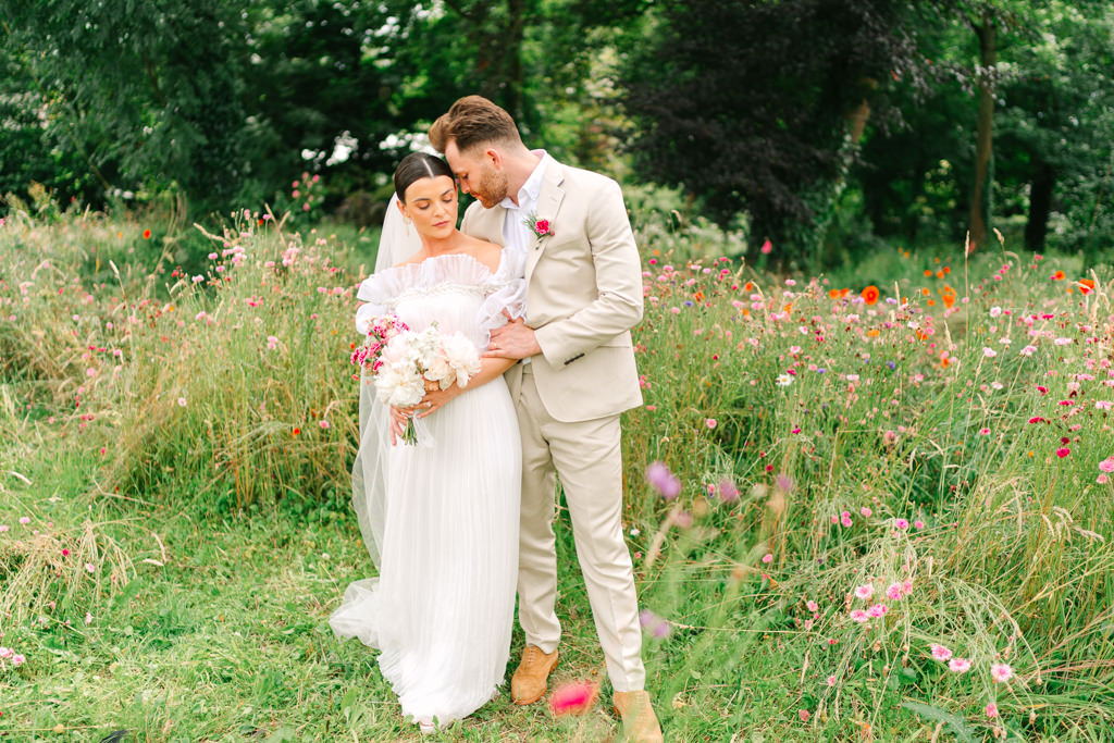 Groom kisses brides cheek in the garden park