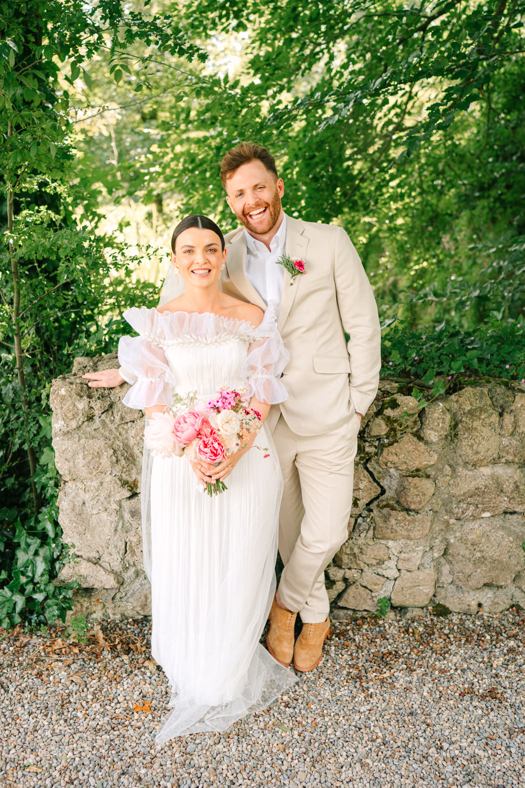 Bride and groom stand in garden park and smile